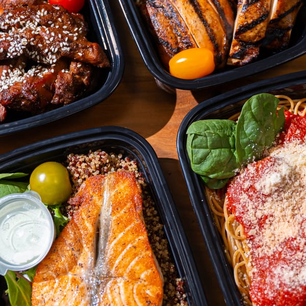 Four meal prep containers with grilled chicken, salmon, pasta, and sesame chicken, each with sides.