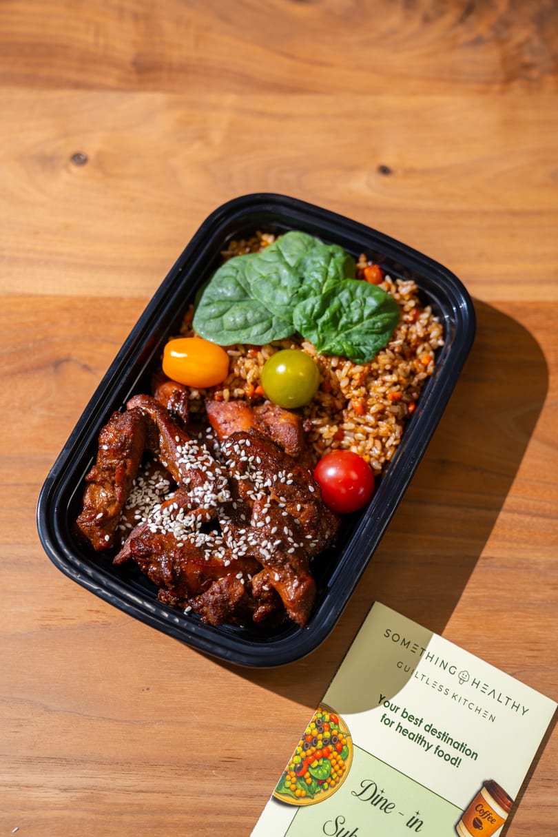 A Something Healthy Guiltless Kitchen meal prep container with chicken, rice, spinach, and tomatoes.