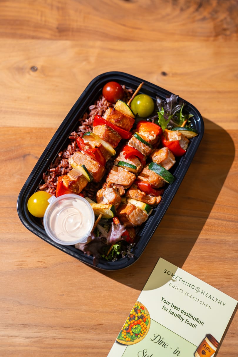 Something Healthy Guiltless Kitchen meal with chicken and vegetable skewers, rice, and a side of sauce.