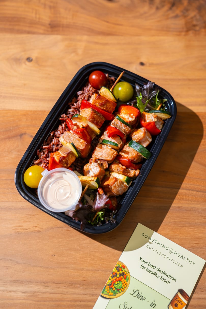 Something Healthy Guiltless Kitchen meal with chicken and vegetable skewers, rice, and sauce.